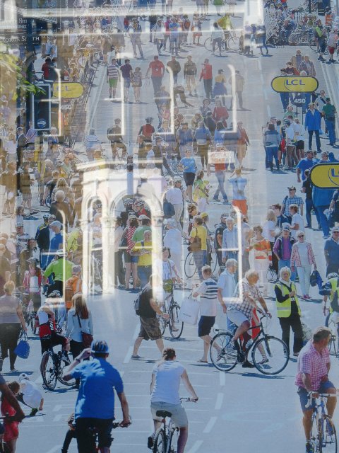 A shot of the crowds enjoyng the party atmosphere before the riders arrived.   Just as visible  is Harrogate's skyline, reflected in the shop-window where this picture was exhibited