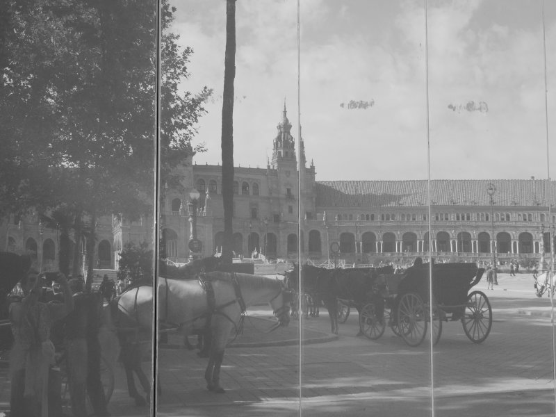 A view of Plaza de España, and the popular horse-drawn carriages of Seville, seen reflected in the windows of the public toilets. 